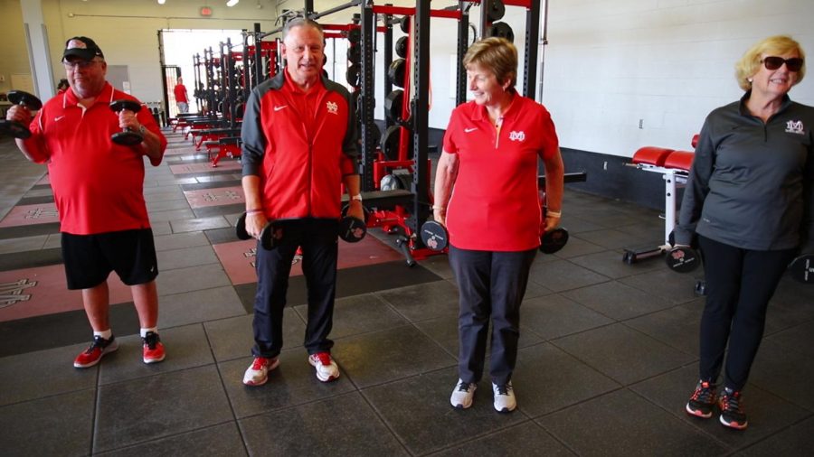 Basketball Coach Gary McKnight, President Patrick Murphy, Principal Frances Clare, and Director of Campus Ministry Helen Steves work out in the school's weight room to promote this Friday's 1950 Day. The four - titled the "fabulous five" by Director of Estate and Alumni Giving Allison Bergeron - will be featured, along with football Coach Bruce Rollinson in Wednesday's promotional video on Monarch Television. The video will also be shared on YouTube and social media. Together, the five have 168 collective years of service to Mater Dei, Bergeron said. “The video will give you a good laugh," said Whitney Pavlik, coordinator of estate and alumni giving.