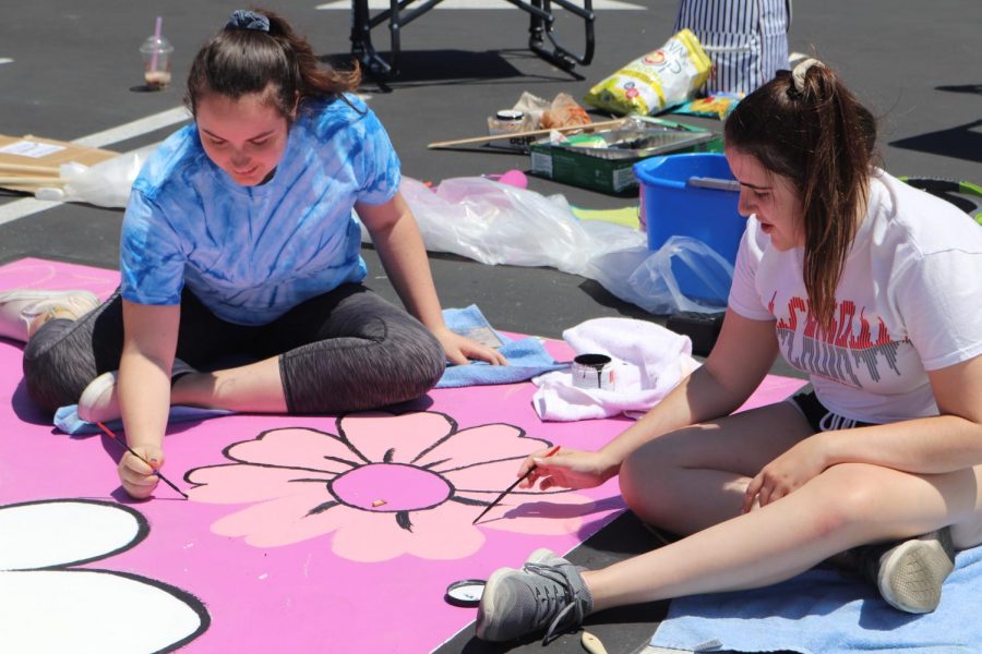 PAINTING PARTY: Senior Beth Romeyn and senior Chloe Savard work together to paint Romeyns personal parking spot for the 2019-2020 school year on Aug. 12. Romeyn was inspired by the Beatles song, Let it Be, and decided to create a pun by replacing the word be with a drawing of a bee. I decided to paint Let it ‘Bee,’ because as a child my Aunt would call me Bee, short for Beth, so I thought it would be nice to have on my spot as something that represents me Romeyn said.