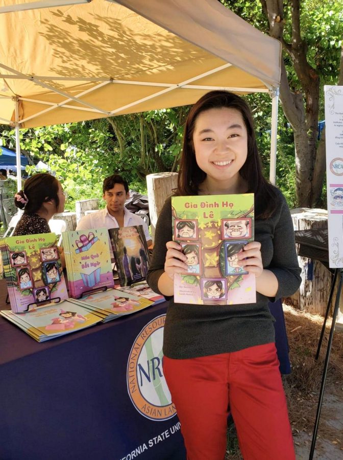 A picture of Le with her book at an NRCL booth which is the competition that she wrote the book for at 15.