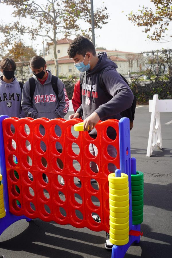 BUILDING COMMUNITY: Freshmen Antonio Taormina, Mikey Erickson, and Santiago Lopez gather in the Bristol Lot for a game of Connect Four. Connect Four was just one of the many games offered during Freshman Fun Day. Other options included cards and checkers. “I was talking with my friends for a bit and messing around with the games. Overall I thought it was pretty fun,” Lopez said. 