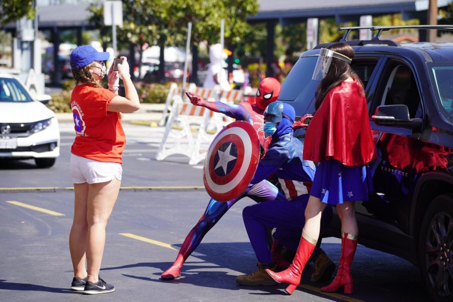 PHOTO TIME: Interacting with families, superhero characters welcome cars and participants. Senior Kaitlyn Ambriz Holl was in charge of taking photos for this station of the parade. The event is filled with nothing but love and fun. There is no other place where you can experience anything like it, Holl said.