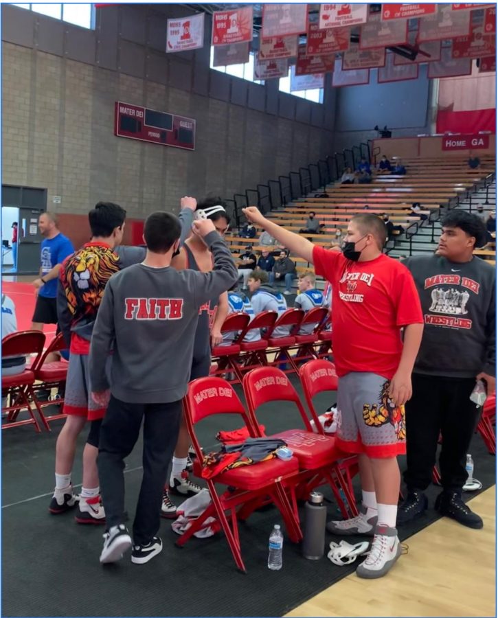 PREP TALK PEP TALKS: (left to right) Junior Luke Couglin, Senior Jake McLaughlin, Freshman Ezekiel Tacket and Freshman Jaycob Renteria give Senior varsity wrestler David Carrillo one last pep talk before he heads into his next match, giving him the motivation to give his all. This perfectly captures the spirit of the Mater Dei wrestling team, as described by the players. “We all support each other, and we all push each other to go further. “If someone is lacking, or [falling] behind we’ll motivate them to keep up.” Carillo says.