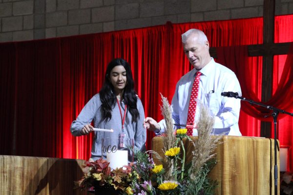 PEACE FOR THE WORLD Mater Dei President Michael Brennan and sophomore Alexa Giries light the peace candle at the beginning of the Respect Life Mass, praying for an end to all life-threatening violence. On Tuesday, Oct. 17 Mater Dei held an all school Mass to honor Respect Life Month. The Monarch community had the opportunity to pray together for peace and the preservation of all life. “Respect Life Month is a period of time where you can really dedicate [yourself] to prayer, praying for life and working towards improving life for all people,” sophomore Evan Nguyen said. Photo courtesy of Katherine Ruiz.