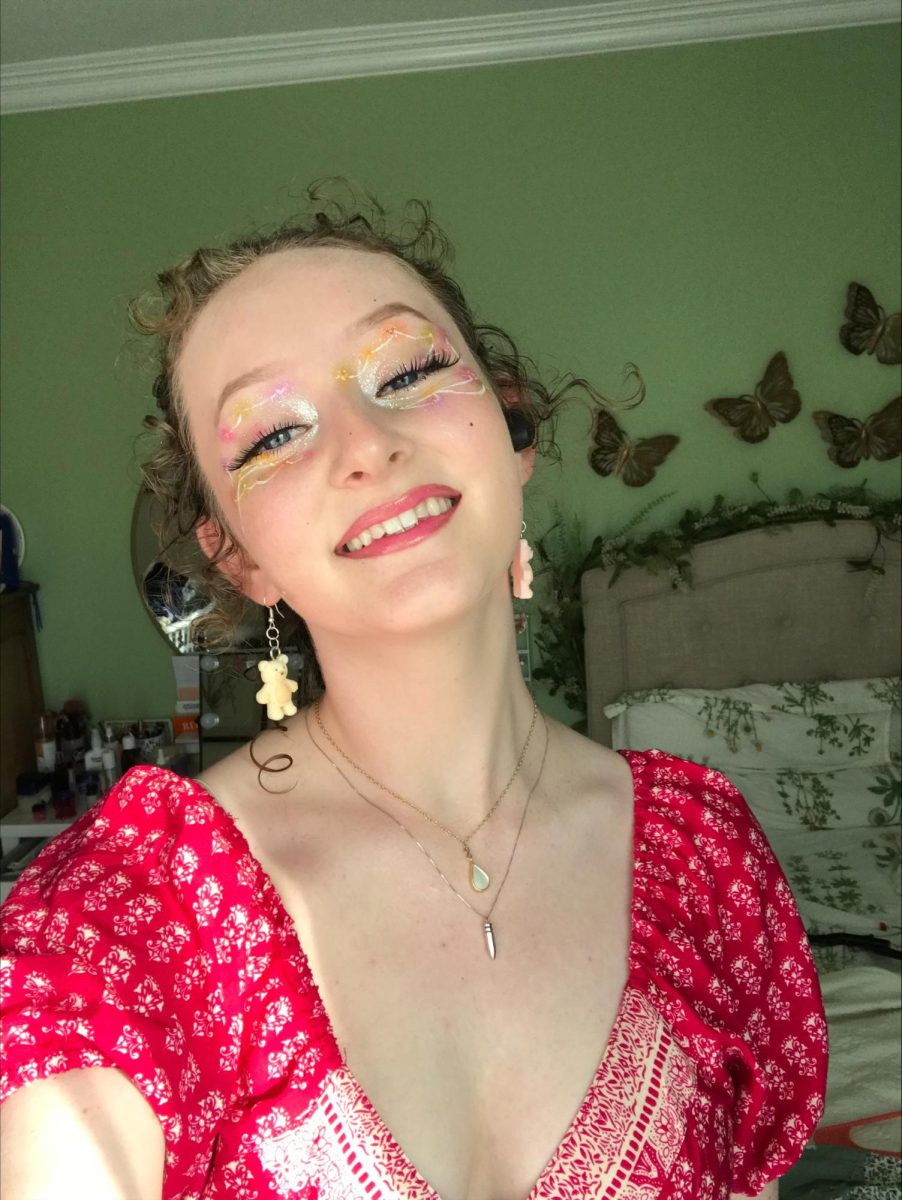 FLOWER POWER: Senior Sam Wurts smiles at the camera, showing off her one of a kind makeup look. Focusing on eye makeup, Wurts brings in soft 70’s colors with matching lipstick. Inspiration is strong, as Wurts’ art comes to life alongside eras of well known styles. 
