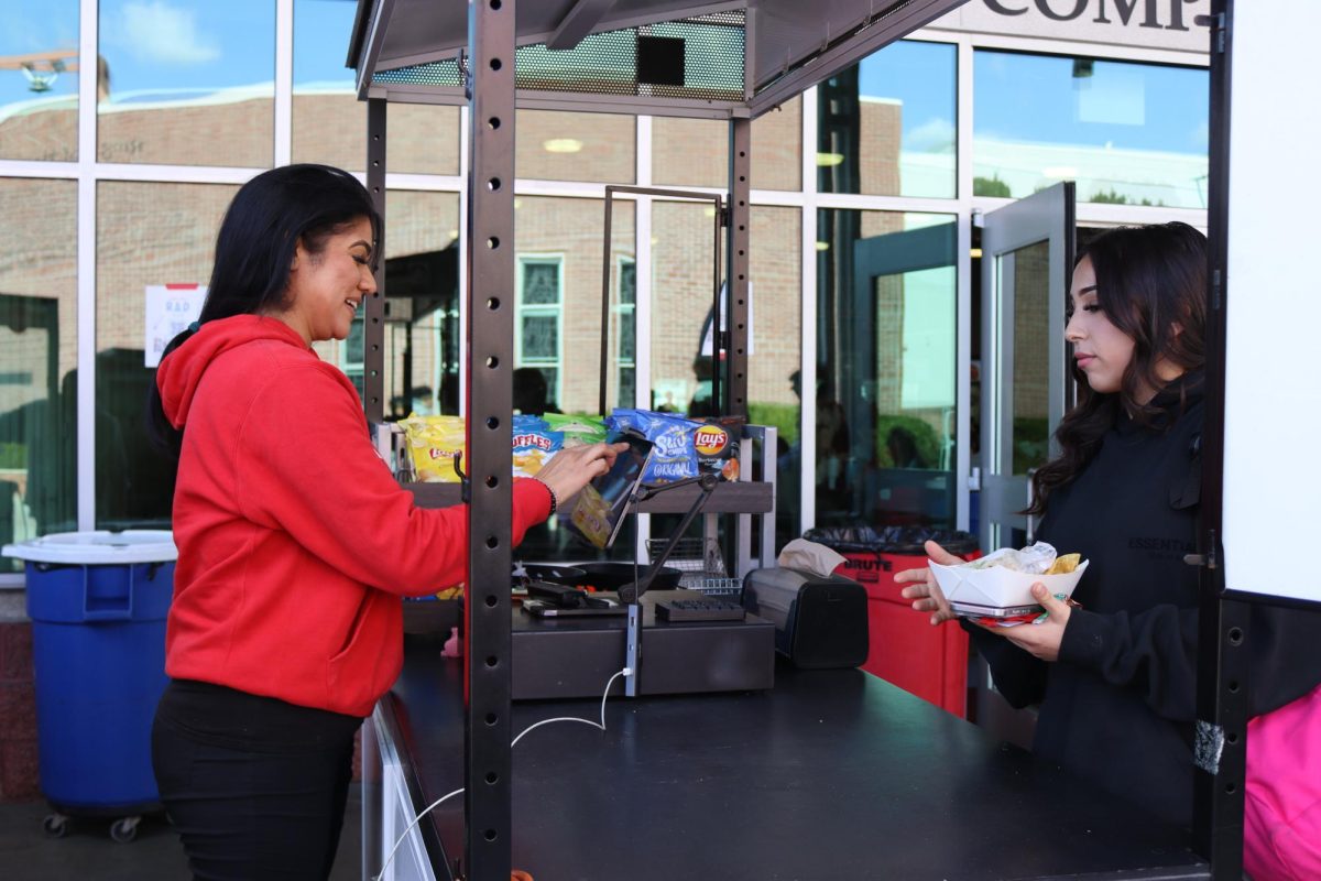 A TASTY TREAT Senior Samantha Arce buys quesadillas and cookies at the international cart during upper lunch. The international cart offers rotating cultural specials from many different cultures as well as chips each day. The quick and friendly transaction provides an easy way for students to grab a delicious bite to eat.