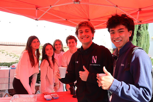 HOT COCOA IN COLD WEATHER Seniors Kalani Kunimura (far right) and Dalton Bulowski (second right) celebrate the holiday season with a cup of hot cocoa, handed out by the Parent Association Council during upper lunch. On Monday, Dec. 2, Monarchs kicked off the Christmas Spirit Week, transforming the campus into a Winter Wonderland with festive all-white snow day outfits. “It’s awesome to celebrate Christmas culture with the Mater Dei community,” Bulowski said.