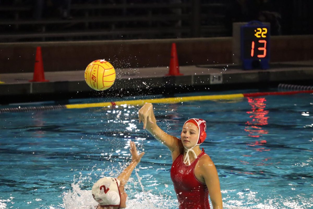 MAKING WAVES Junior and driver Ayla Ackerman shoots the ball while an opposing player attempts to guard her. The Mater Dei Varsity Girls Water Polo Team faced off against the Laguna Beach Breakers on Dec. 13 in a legendary match. The Monarchs won the game with a final score of 12-6. Not only did these girls demonstrate their shooting accuracy, swimming speed, and excellent teamwork, they displayed their passion and dedication for the sport. “I would say [water polo has taught] me perseverance, resilience, discipline, and to trust my teammates and coaches,” senior Mia Sullivan said. Photo by Paige Deiparine.