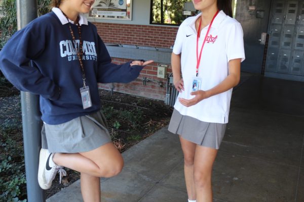 DRESSED AND READY Sophomores Isabella Waddington and Sylvie Ceran are seen conversing by the Grotto. Both students wear the Mater Dei uniform and their student ID cards, along with the appropriate, student handbook required minimum length of the skirt. “In my opinion, the uniforms at Mater Dei are the highlight of going here,” Ceran said. Photo Illustration by Sheridan Hofer.