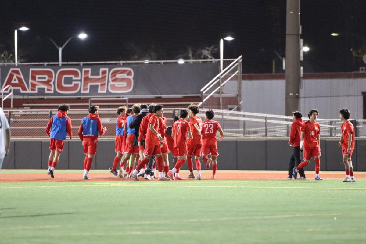 GOAL GLORY: The Mater Dei Varsity Boys Soccer Team gathers on the field celebrating a wonderful match. With determination and teamwork, the athletes showed Servite the spirit of  competition and school pride. “It was a tough game for us,” Pham said. “Coach Ganey and the team prepared for this game carefully, so that is the main reason we had a wonderful victory.”