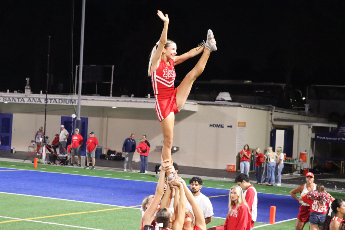 SKY’S THE LIMIT Mater Dei cheerleaders lift up senior Lindsay Brown as she flies in a stunt during the first home game of the football season. On Friday, Sep. 5, the team cheered on the Varsity Football Team to victory against Kahuku High and Intermediate School.
